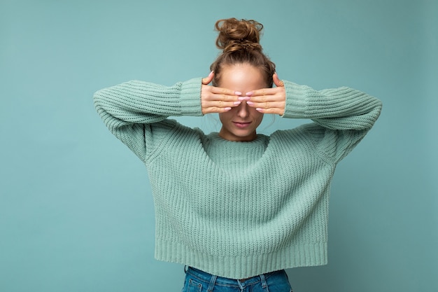 Foto van een jonge, mooie blonde vrouw met oprechte emoties die een casual blauwe trui draagt, geïsoleerd