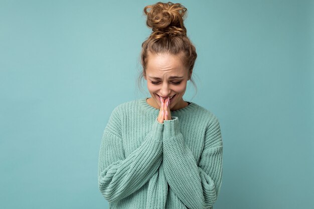 Foto foto van een jonge positieve, mooie blonde vrouw met oprechte emoties die een casual blauwe trui draagt