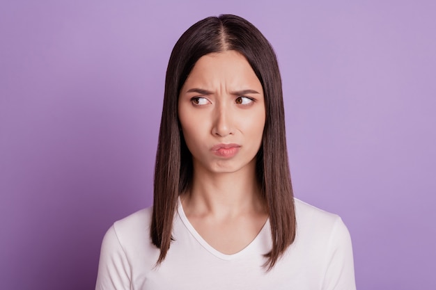 Foto van een jonge vrouw, ongelukkig, verdrietig, overstuur, negatief, humeurig, twijfel, denk, kijk lege ruimte geïsoleerd over violette kleurachtergrond