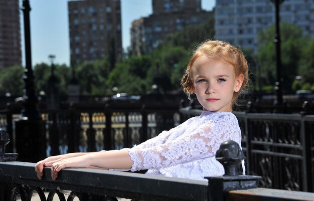 Foto van een klein meisje in een witte jurk die buiten poseert