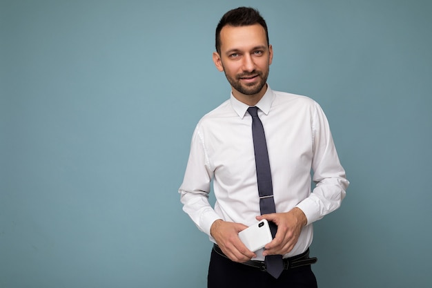 Foto van een knappe, knappe brunet ongeschoren man met baard die een casual wit overhemd en stropdas draagt