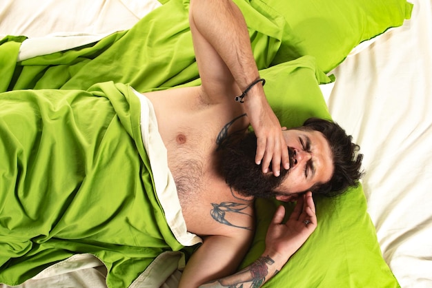 Foto van een knappe man die slaapt en een zacht groen kussen vasthoudt Goedemorgen, blij om te slapen man die slaapt