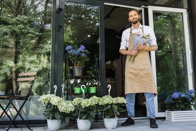 Foto van een knappe man die voor de bloemenwinkel staat