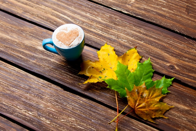 foto van een kopje koffie en herfstbladeren op de prachtige bruine houten achtergrond