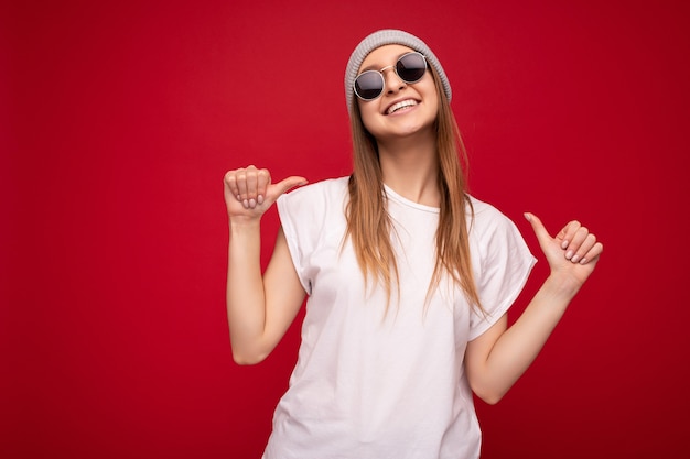 Foto van een leuke, innemende positieve volwassen vrouw die een casual outfit draagt, geïsoleerd op de achtergrondmuur