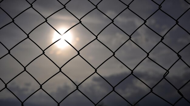 foto van een metalen omheining met gaas bij zonsondergang