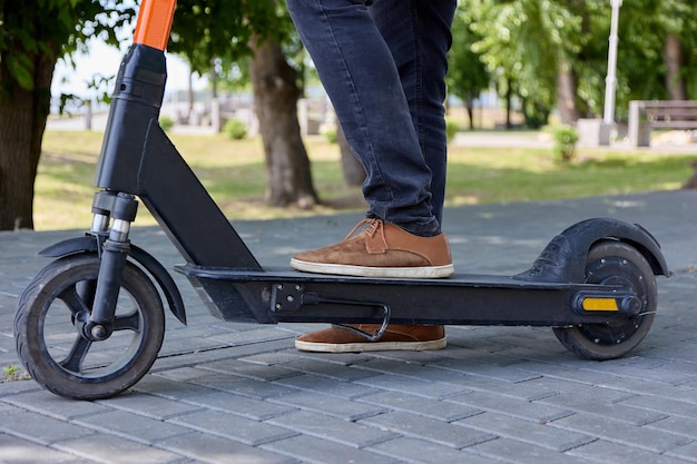 Foto van een moderne elektrische scooter en een man die op straatstenen rijdt