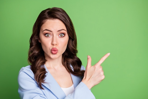 Foto van een mooi krullend kapsel voor dames geeft aan dat de lege ruimte van de vinger een blauwe blazer draagt, een geïsoleerde groene kleurachtergrond