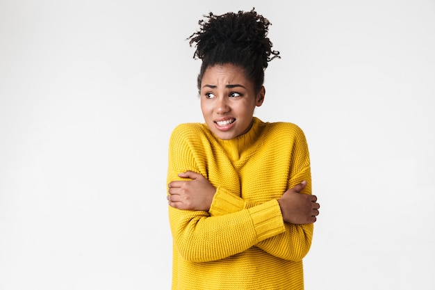 Foto van een mooie jonge emotionele bevroren vrouw in trui die zich voordeed op witte muur.