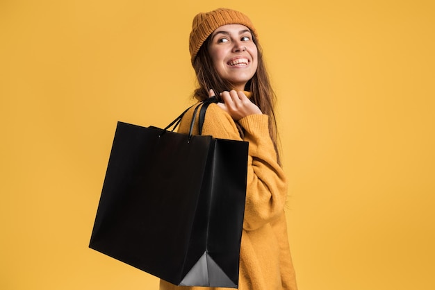 Foto van een mooie millennial-modeldame die veel shopper-packs draagt en wegkijkt voor de camera geïsoleerde gele achtergrond