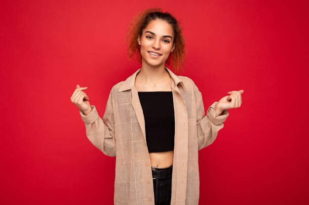 Foto van een mooie positief lachende volwassen vrouw die stijlvolle kleding draagt die geïsoleerd staat op