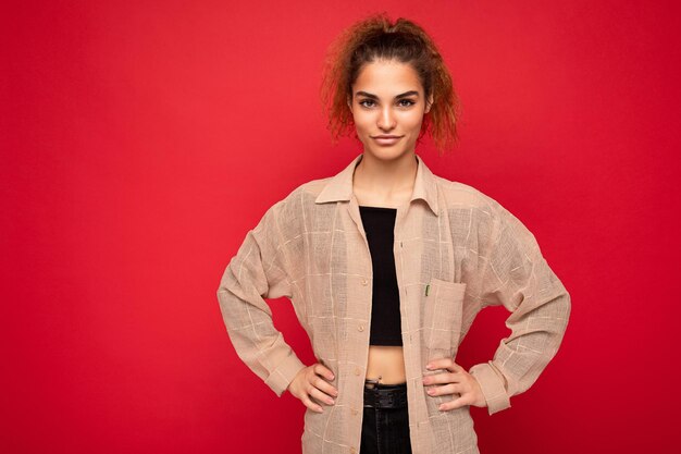 Foto van een mooie positief lachende volwassen vrouw die stijlvolle kleding draagt die geïsoleerd staat op