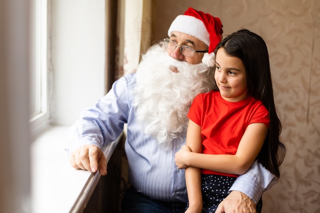 Foto van een oudere man met een kerstmuts tijdens het spelen met zijn kleinkinderen