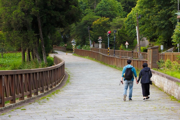 Foto van een paar hand in hand en wandelen op de weg in de buurt van het treinstation van Alishan. Alishan Taiwan