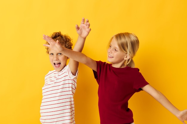 Foto van een positieve jongen en meisje die naast elkaar staan en de emoties van de kindertijd op een gele achtergrond stellen