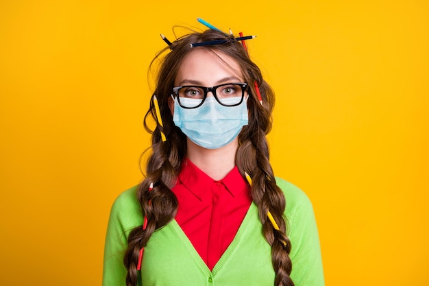 Foto van een serieus meisje met een rommelig kapsel, draag een masker in geek-stijl outfit geïsoleerd op een gele achtergrond