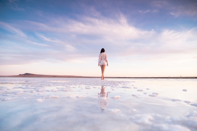 Foto foto van een slanke vrouw van achteren met weerspiegeling in het water.