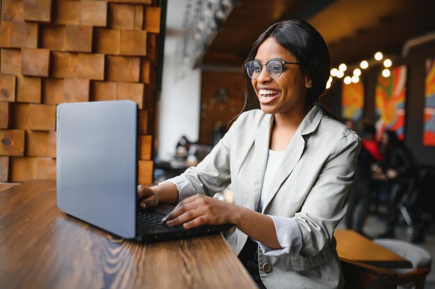 Foto van een vrolijke, extatische, dolgelukkige ondernemer van gemengd ras die het bedrijfsinkomen ziet toenemen met laptop.