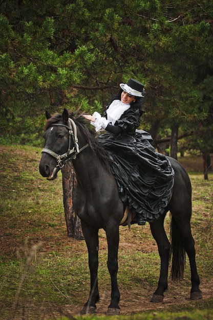 Foto van een vrouw in een prachtig theaterkostuum, te paard in de natuur