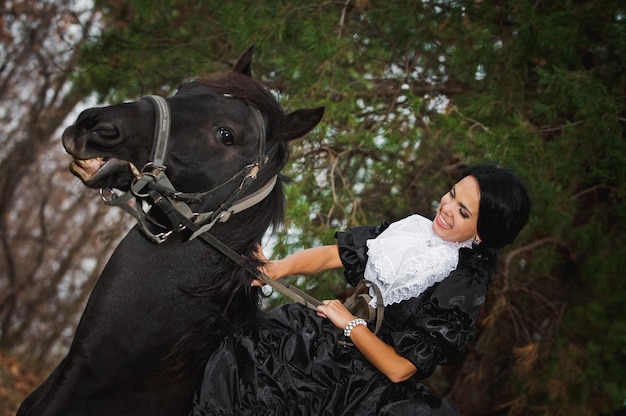 Foto van een vrouw in een prachtig theaterkostuum te paard in de natuur