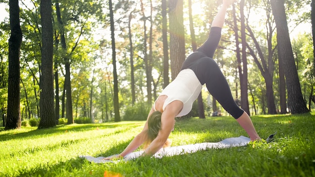 Foto van een vrouw van middelbare leeftijd in sportkleding die buiten yoga beoefent in het park. Vrouw van middelbare leeftijd die zich uitstrekt en mediteert in het bos
