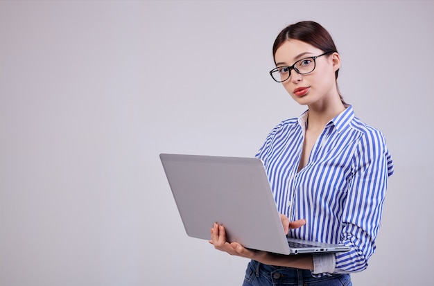 Foto van een vrouwelijke beheerder in een gestreept wit-blauw shirt met een bril en een laptop