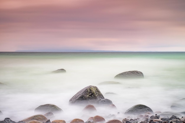 Foto van een zonsondergang met lange belichting op het strand van de Oostzee paarse horizon