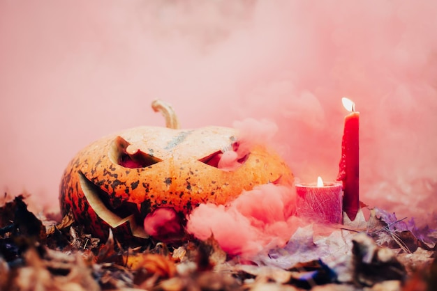 Foto van enge halloween-pompoen met brandende kaarsen in rode kleurrijke rook Griezelige sfeer halloween-viering