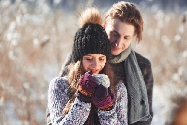 Foto van gelukkig man en mooie vrouw met cups buiten in de winter. Wintervakantie en vakantie. Kerst paar gelukkige man en vrouw drinken warme wijn. Verliefd stel