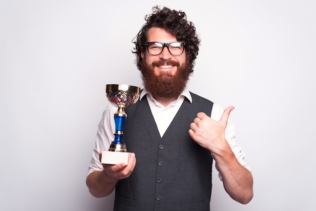 Foto foto van gelukkige blanke man met cup award en duim opdagen