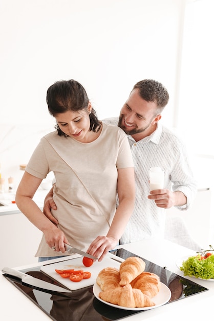 Foto van gelukkige familie vrouw en man 30s koken, en het voorbereiden van ontbijt in huis keuken