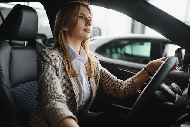 Foto van gelukkige jonge vrouw zit in haar nieuwe auto. Concept voor autoverhuur