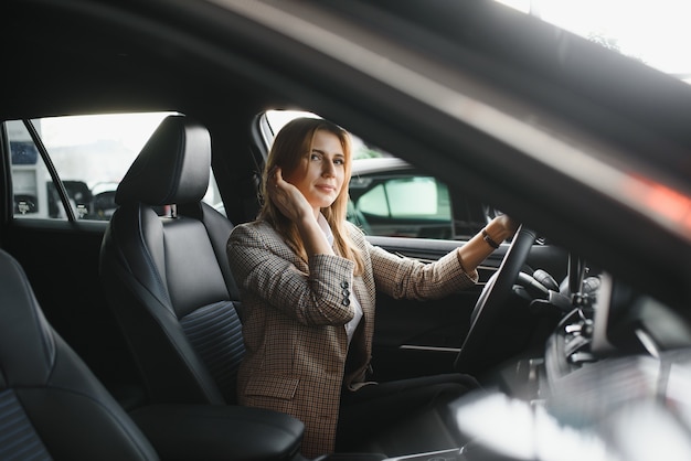 Foto van gelukkige jonge vrouw zit in haar nieuwe auto. Concept voor autoverhuur