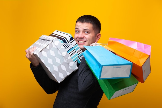 Foto van gelukkige mannelijke shopper met papieren zakken en dozen