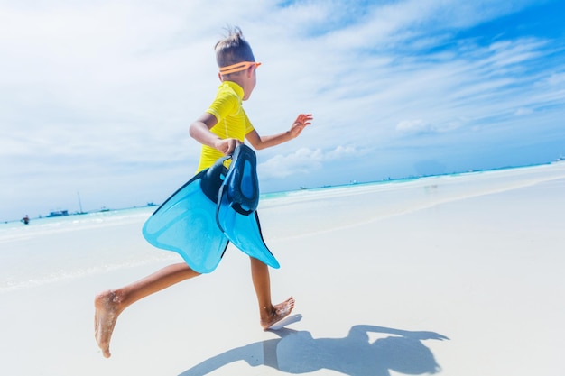 Foto van gelukkige snorkelende jongen in gele zwemkleding op het witte strand