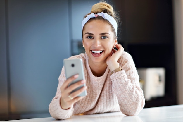 Foto van gelukkige vrouw die sms't in de keuken