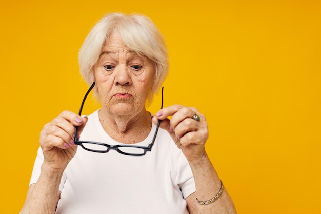 Foto van gepensioneerde oude dame problemen met het gezichtsvermogen met een gele achtergrond van een bril