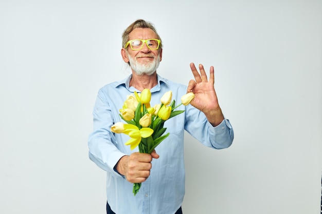 Foto van gepensioneerde oude man een boeket bloemen met een bril als een geschenk lichte achtergrond