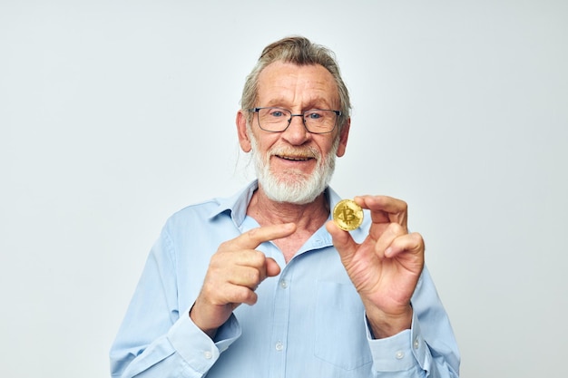 Foto van gepensioneerde oude man financiert gouden munten bitcoin poseren geïsoleerde achtergrond