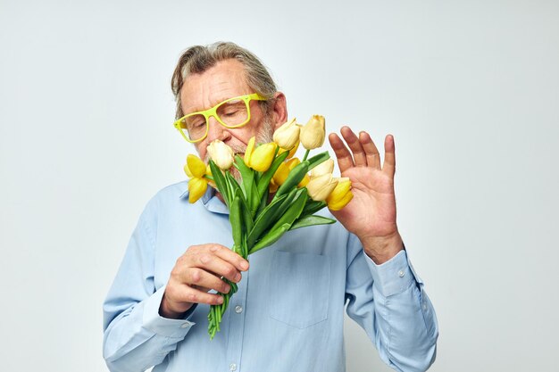 Foto van gepensioneerde oude man geel boeket bloemen poseren lichte achtergrond