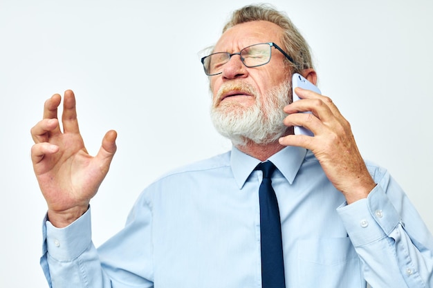 Foto van gepensioneerde oude man in een overhemd met een stropdas praten aan de telefoon geïsoleerde achtergrond