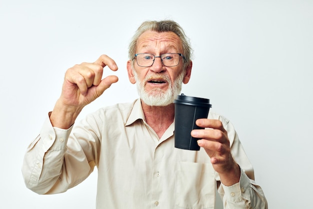 Foto van gepensioneerde oude man met een grijze baard in een shirt en een lichte achtergrond van een bril