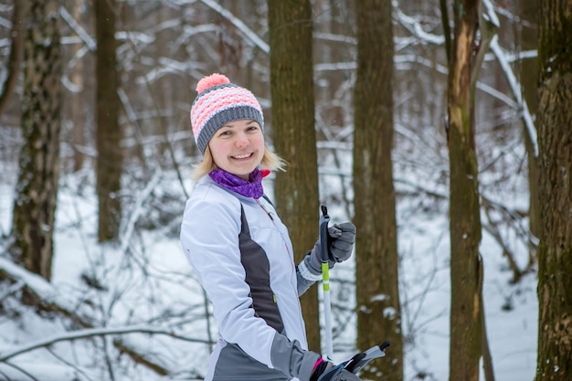 Foto van glimlachende vrouw met ski's in de winterbos