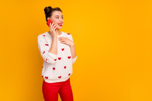 Foto van grappige energieke dame houdt telefoongesprek beste vriend vertelt romantisch date verhaal geïnspireerd slijtage harten patroon witte trui