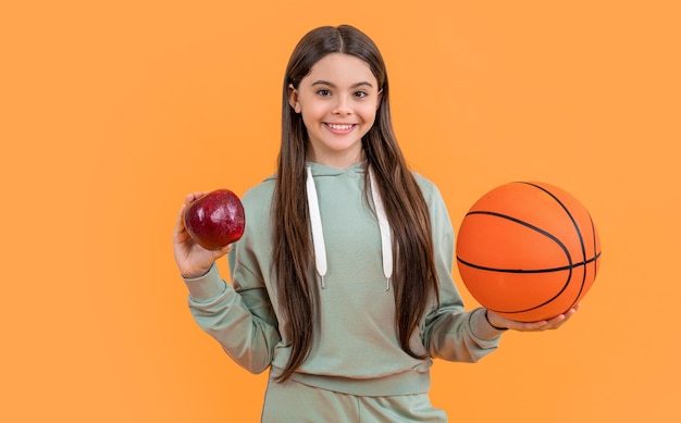 Foto van het gelukkige meisje van het tienerbasketbal met het meisje van het appeltienerbasketbal dat op geel wordt geïsoleerd