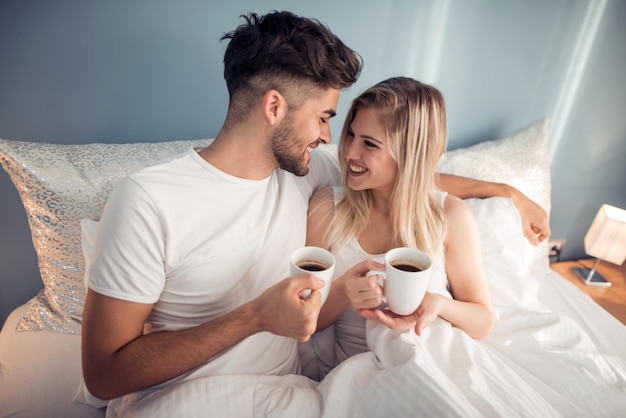 Foto van jong stel dat koffie drinkt in bed