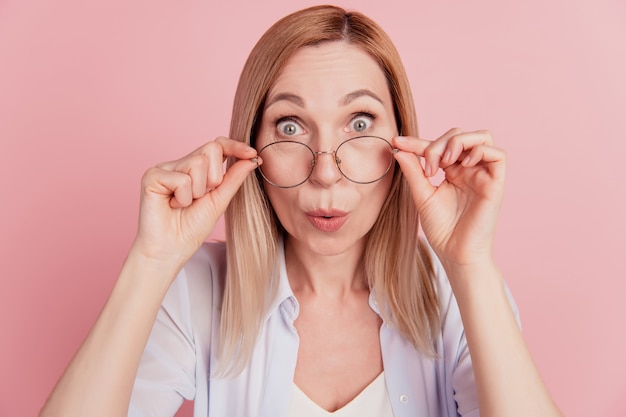 Foto van jonge aantrekkelijke vrouw verbaasd geschokt verrast handaanraking bril geïsoleerd over roze kleur achtergrond