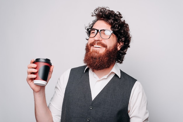 Foto van jonge bebaarde hipster man in pak glimlachend en koffie drinken, tijd om te ontspannen