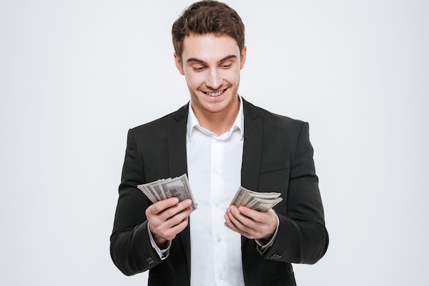 Foto van jonge gelukkige zakenman die geld in handen houdt. Geïsoleerd over witte muur. Kijk naar geld.