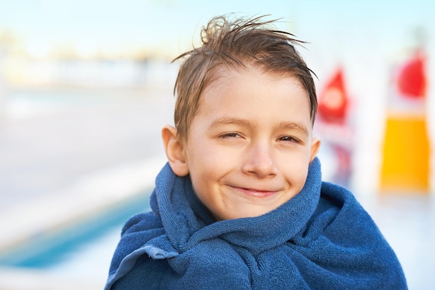 Foto van jonge jongen in handdoek na het spelen in openlucht aquapark